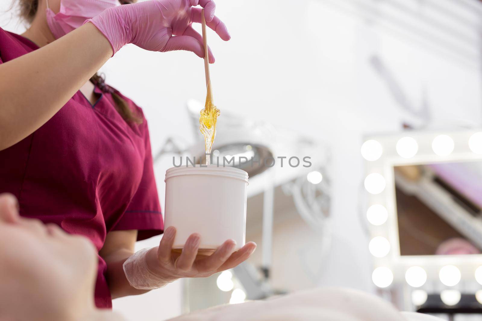 Cosmetician takes the sugar paste from the jar. Shugaring. Sugar paste out of the container with a spatula. Sugar paste for sugaring. Sugaring in beauty salon