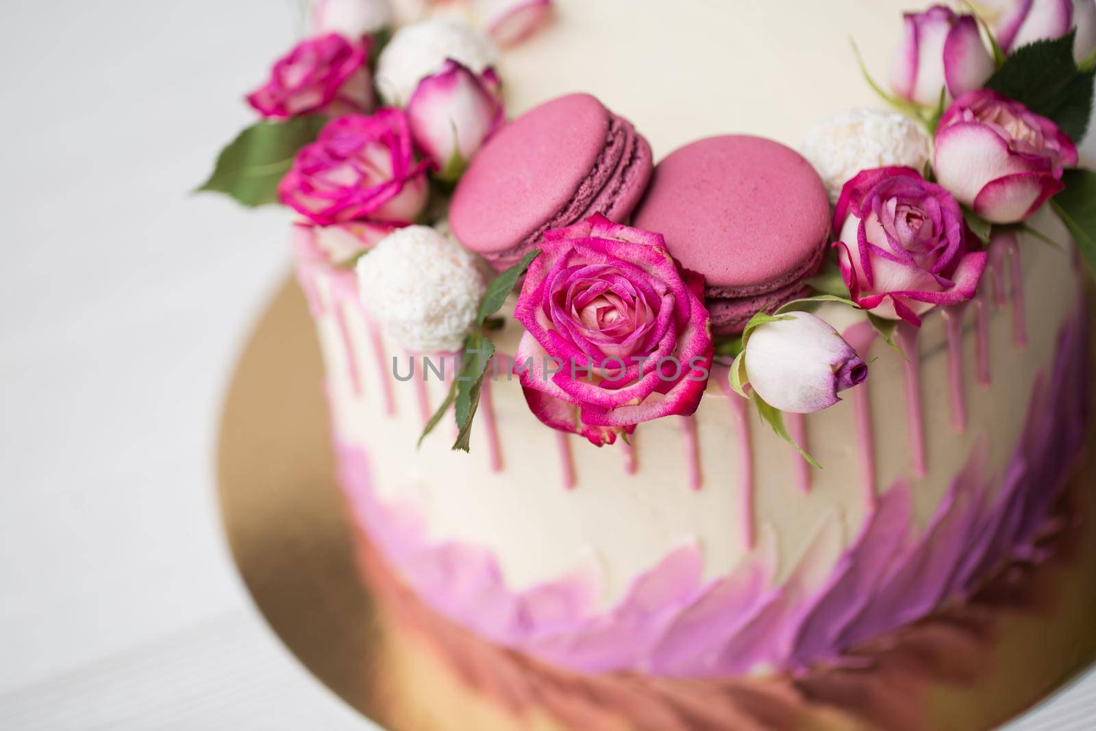 Cake with roses, sweets and lilac macaroons.