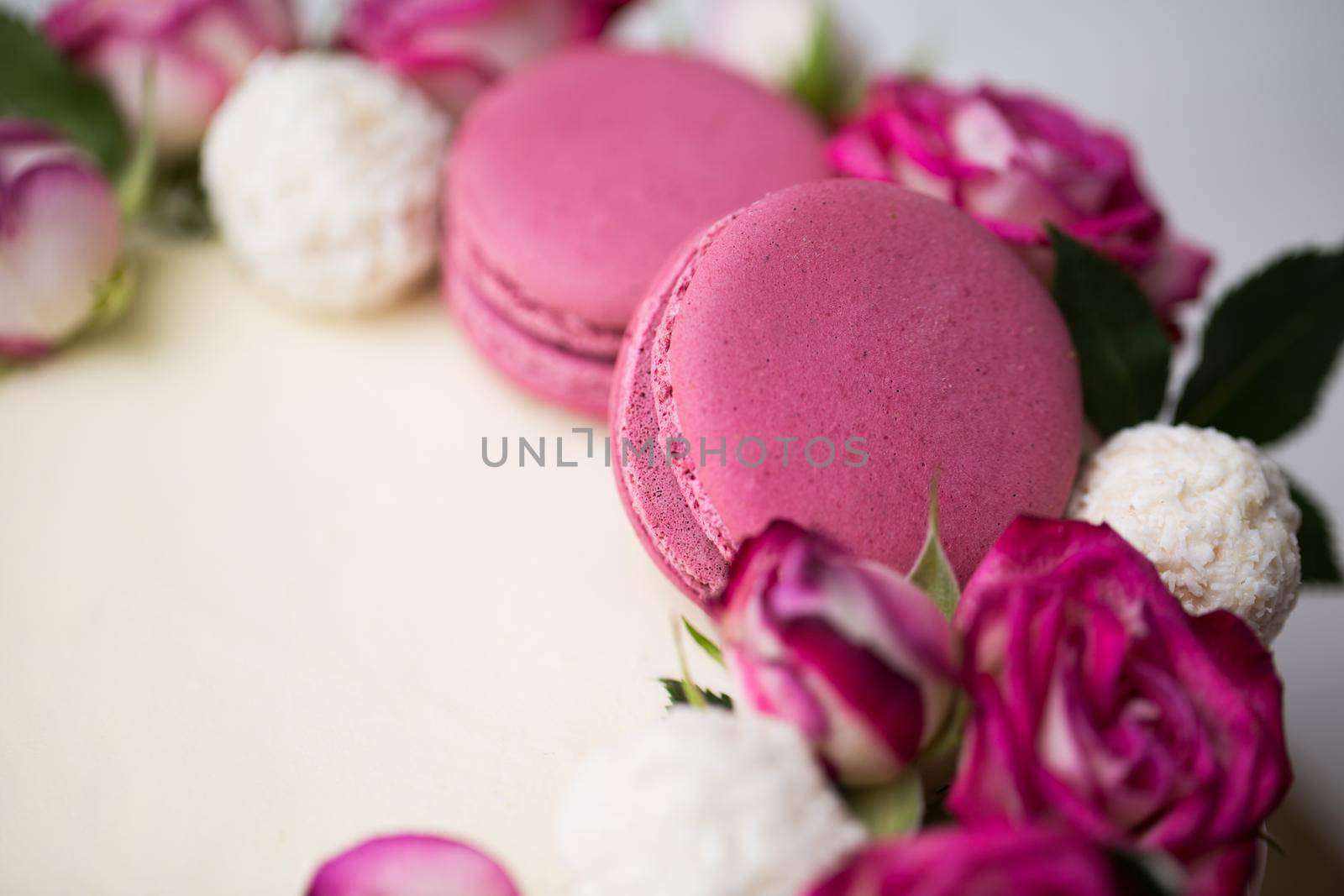 Cake with roses, sweets and lilac macaroons.