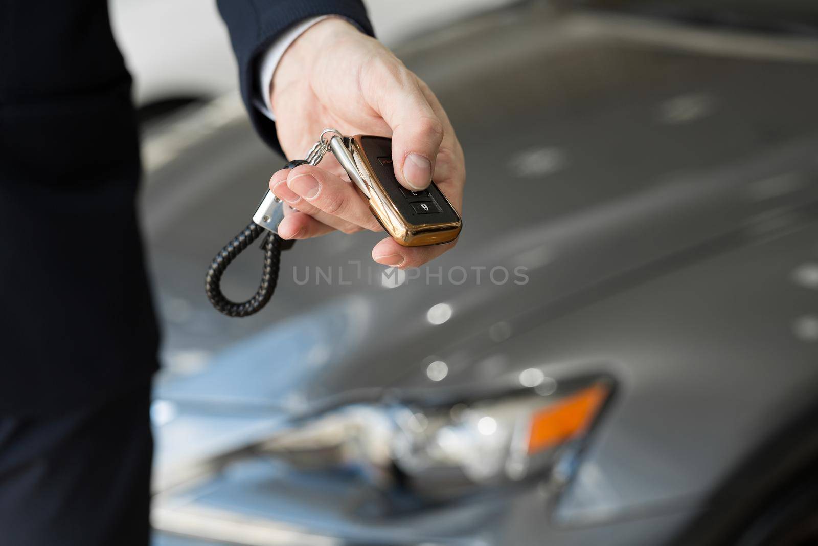 A car dealer with a key in a car dealership close-up. by StudioPeace