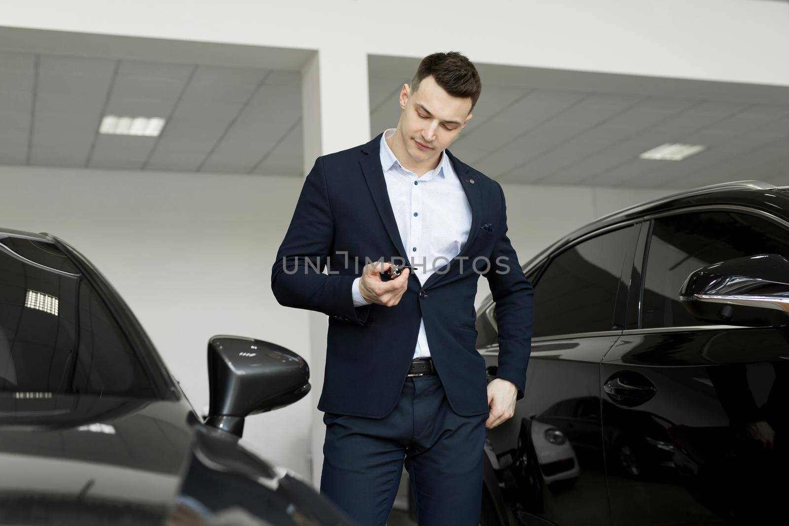 Handsome man choosing a car in a show room. by StudioPeace