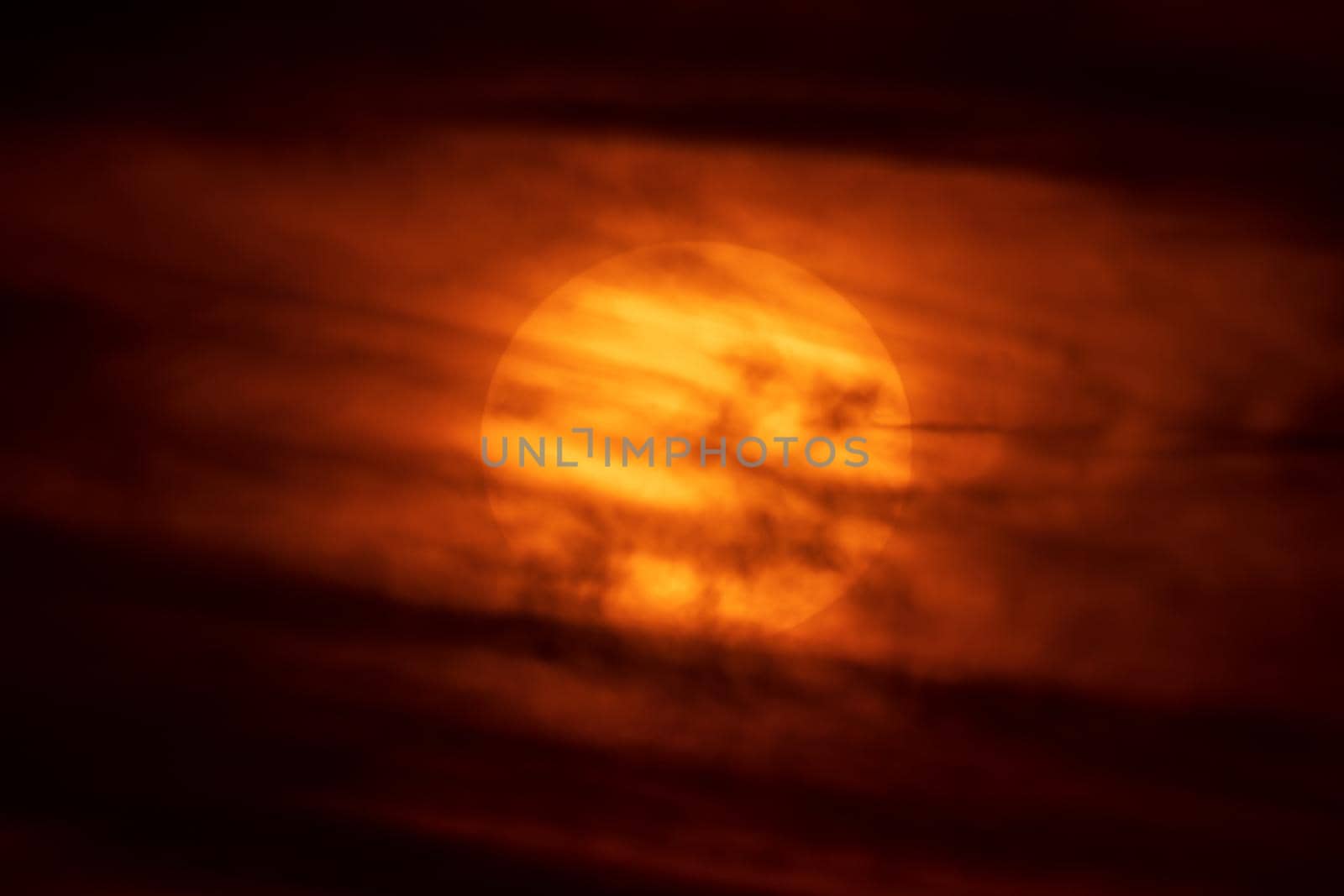 Huge sun at orange sunset covered by clouds by FerradalFCG