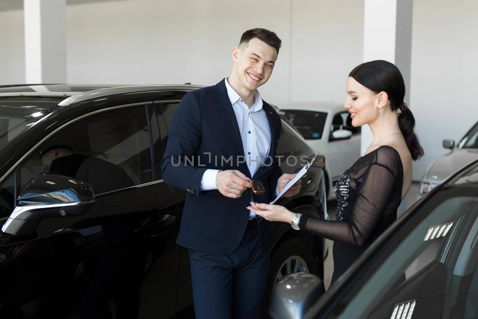 Seller gives the buyer the keys to a new car in the showroom. by StudioPeace
