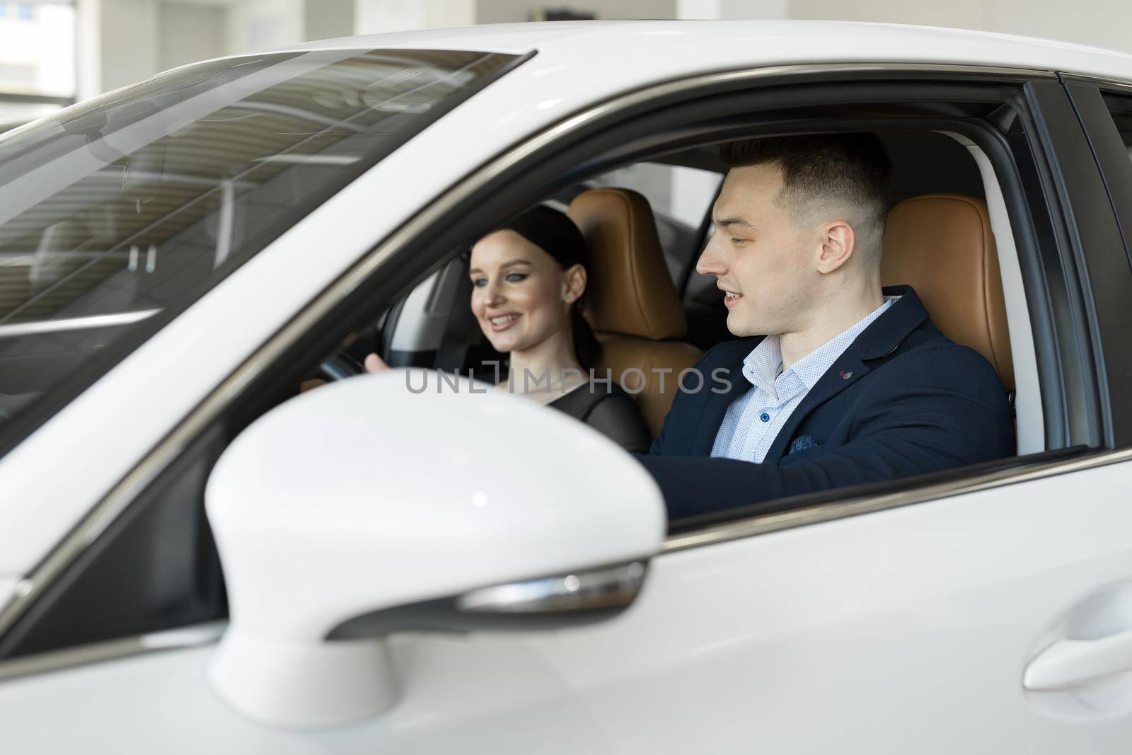 Married couple husband and wife sitting in a car in a car dealership. Test the car before buying by StudioPeace