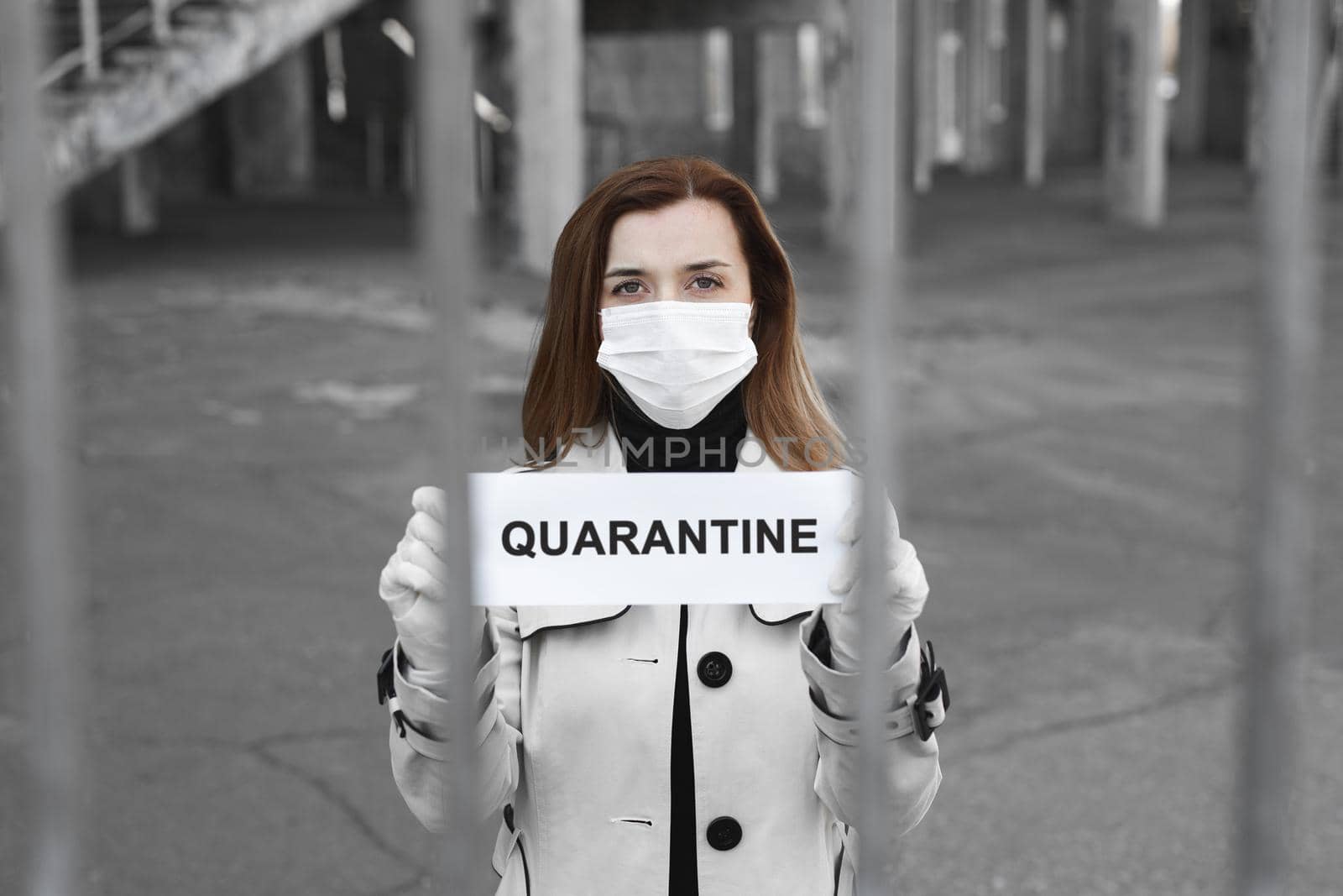 A woman behind bars in isolation holds a placard reading quarantine. Message for the prevention of coronavirus covind-19