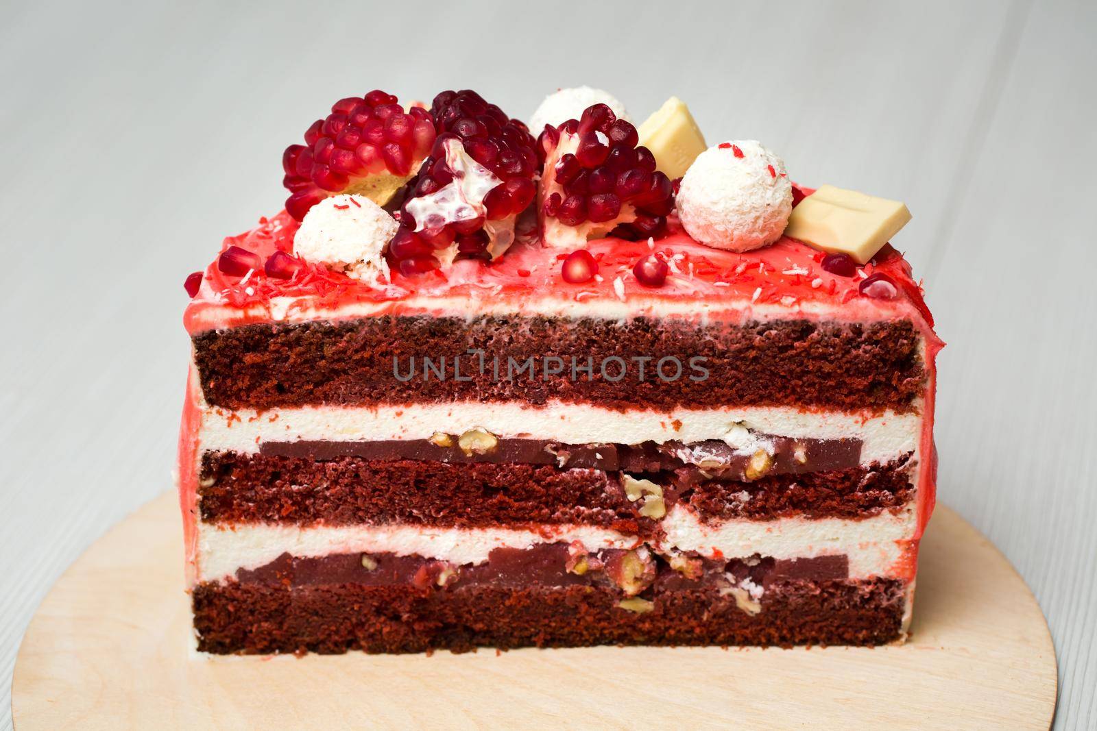 cake with white cream, chocolate drips, pomegranate, nuts and chocolate decor