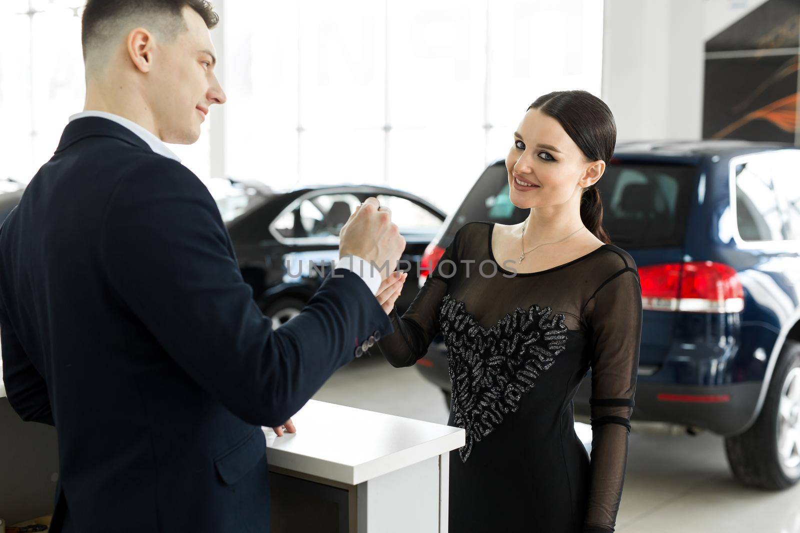 Car rental and Insurance concept, Young salesman receiving money and giving car's key to customer after sign agreement contract with approved good deal for rent or purchase by StudioPeace