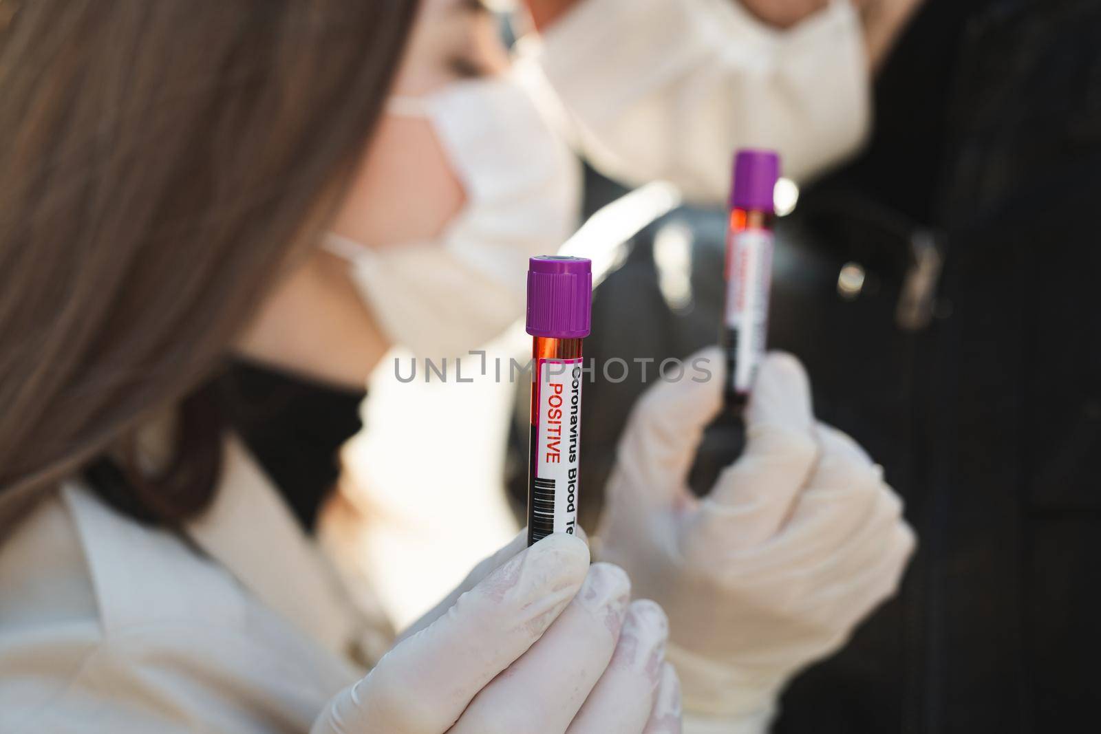 Hands man and woman holds a test tube containing a blood sample, test tube with blood for Covid-19 analyzing. Laboratory testing patient blood. Positive blood test result