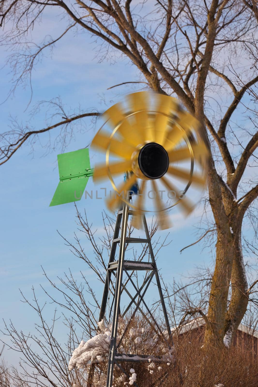 A small Windmill or Wind Turbine in a Rural Setting with Spinning Blades by markvandam
