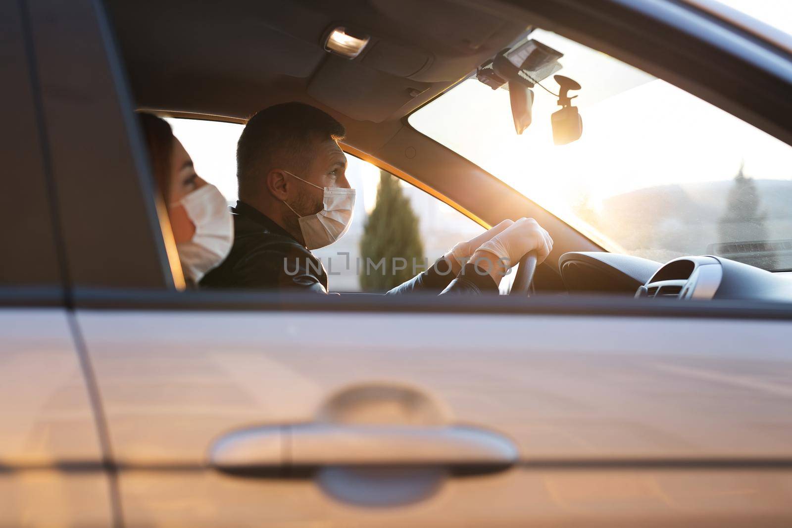 A man and a woman wearing medical masks and rubber gloves to protect themselves from bacteria and viruses while driving a car. masked men in the car. coronavirus, covid-19.