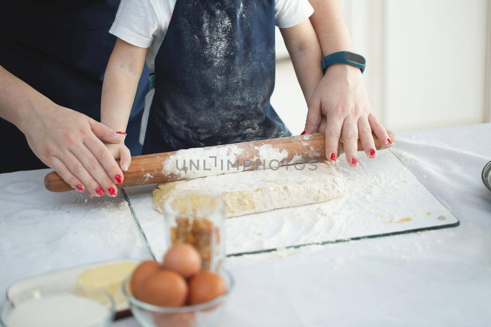 Mother and daughter roll out the dough with a rolling pin. Close-up view. by StudioPeace