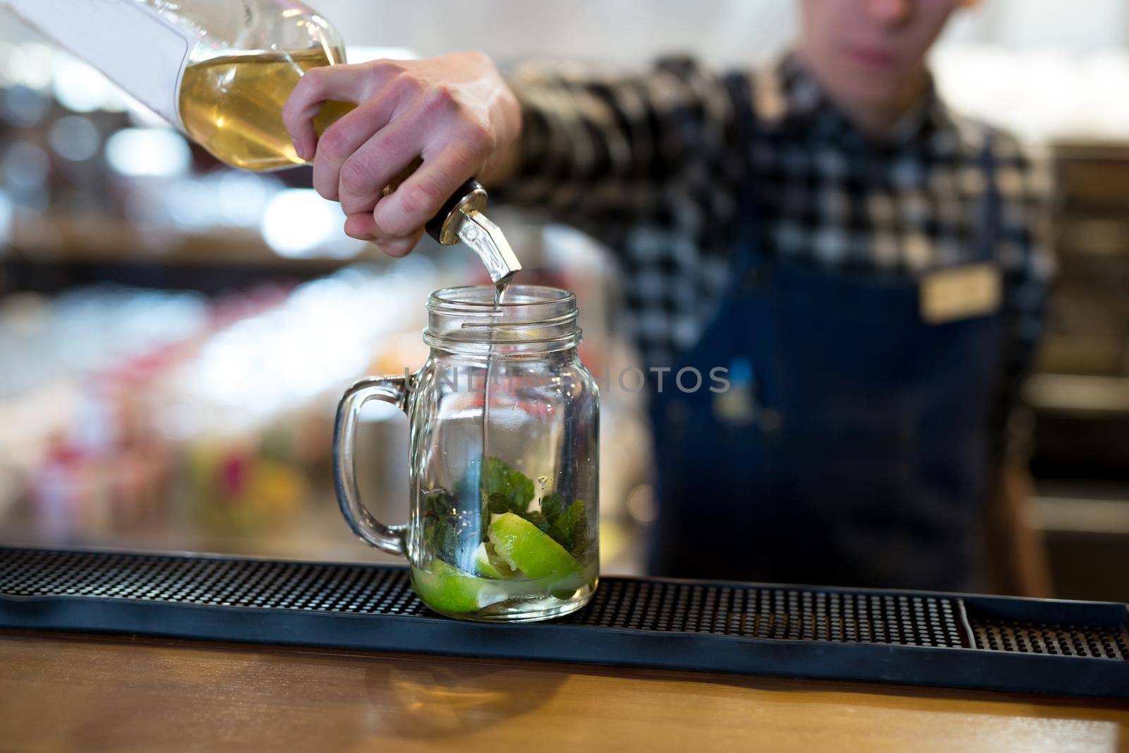 The bartender pours syrup into a cocktail glass.