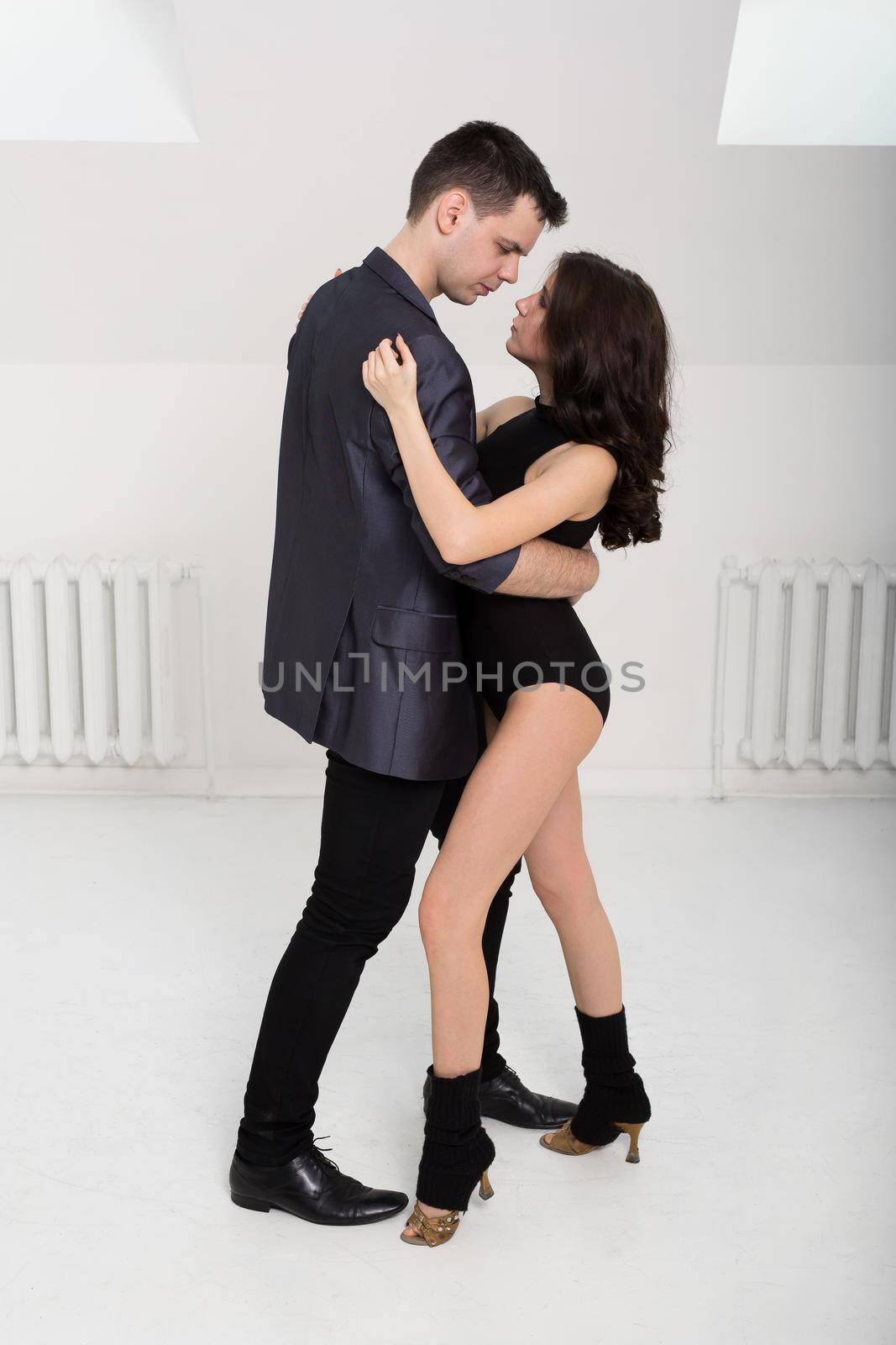 beautiful couple dancing bachata on white background in studio