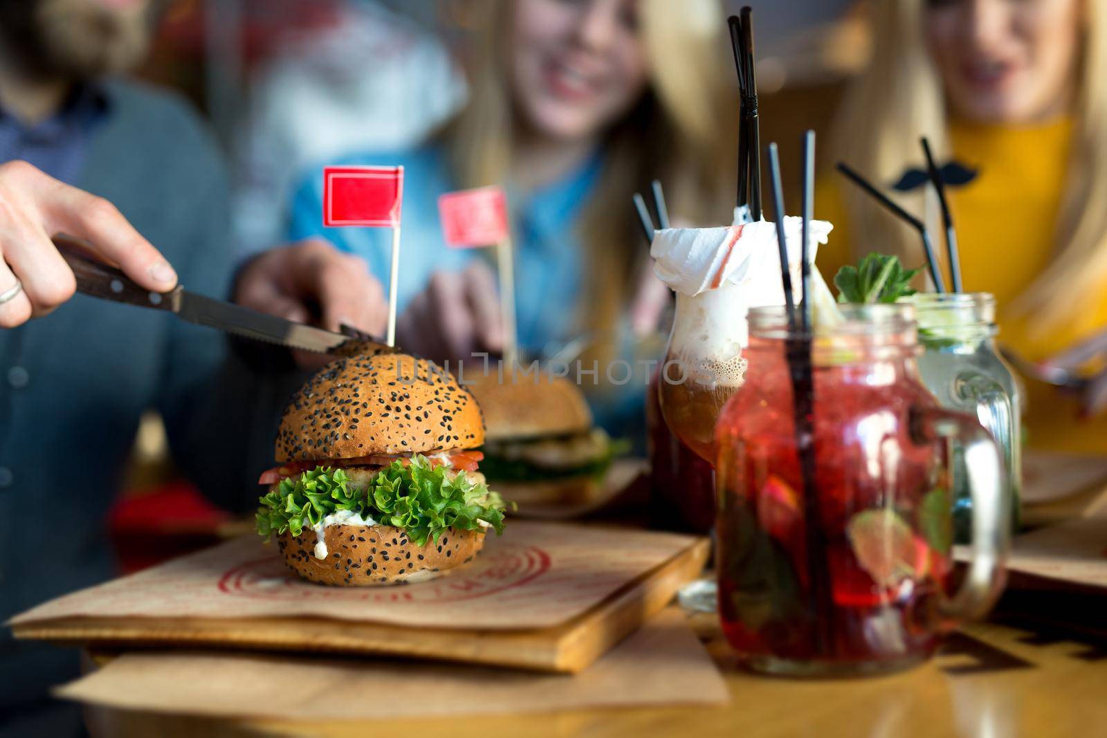 Burger and cocktail on a wooden table in a restaurant close-up.