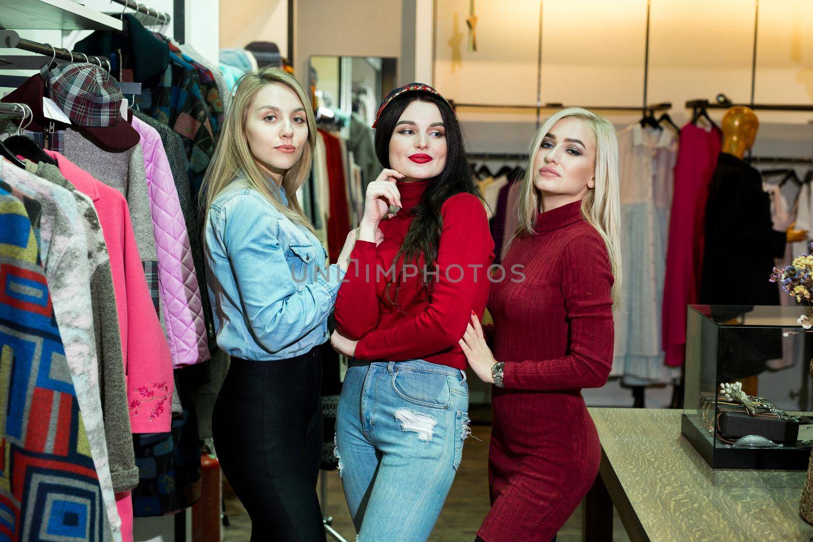 Shopping, fashion and friendship concept - three smiling friends trying on some clothes at shopping mall by StudioPeace