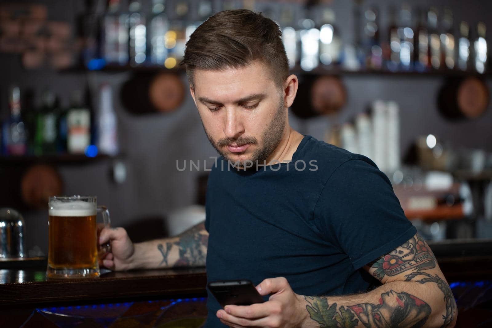 Young man sitting at bar counter with a pint of light beer
