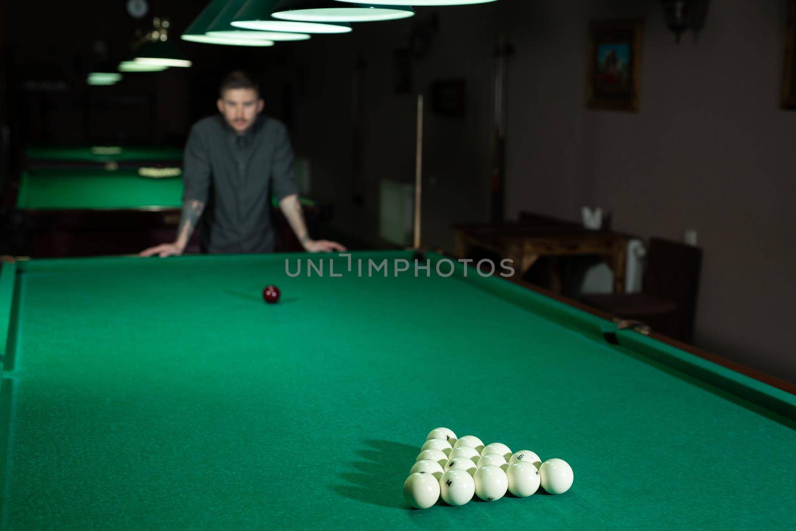 Billiard balls in a green billiard table. A man playing Billiards