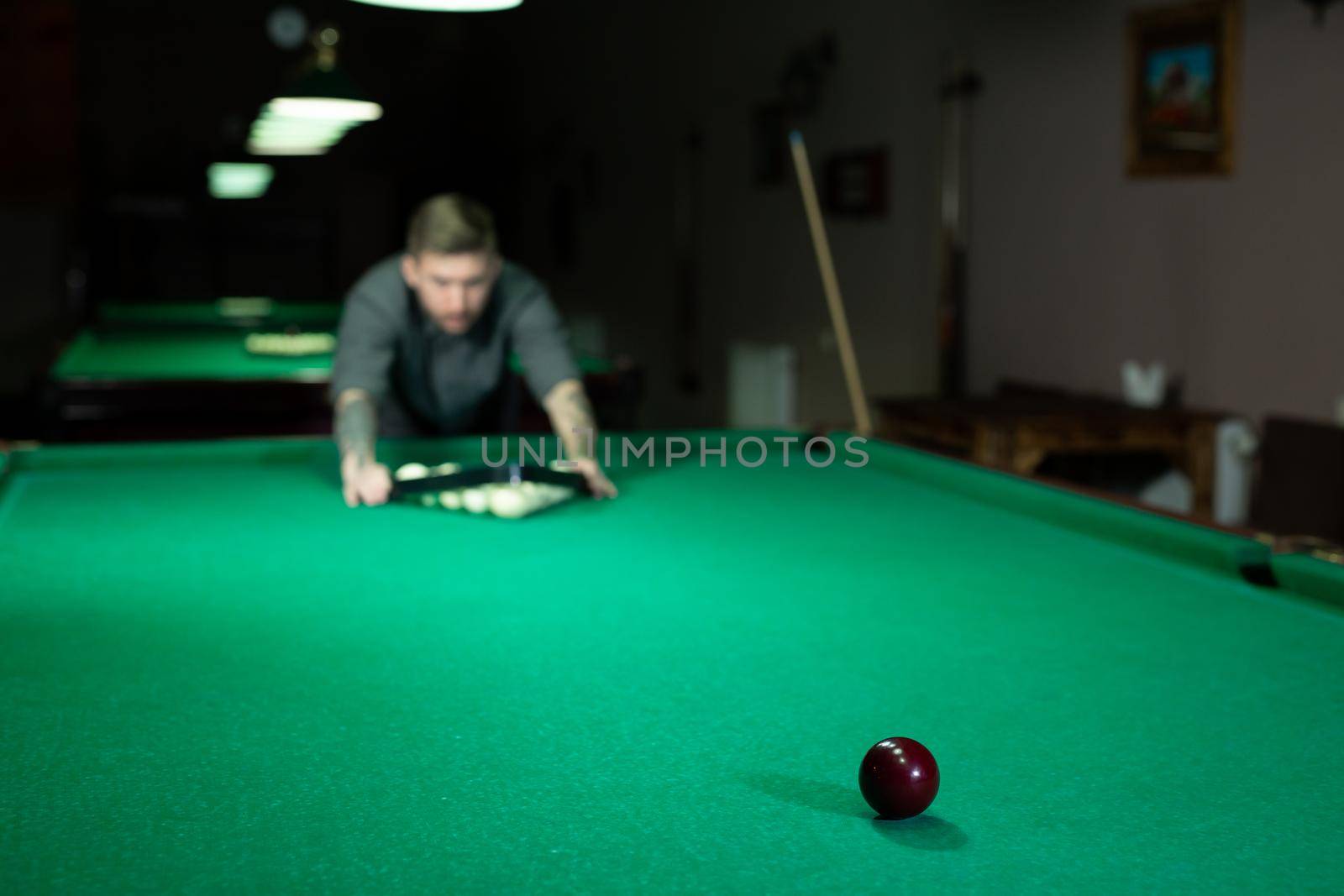 Game of billiards. The man puts the balls on the green billiard table.