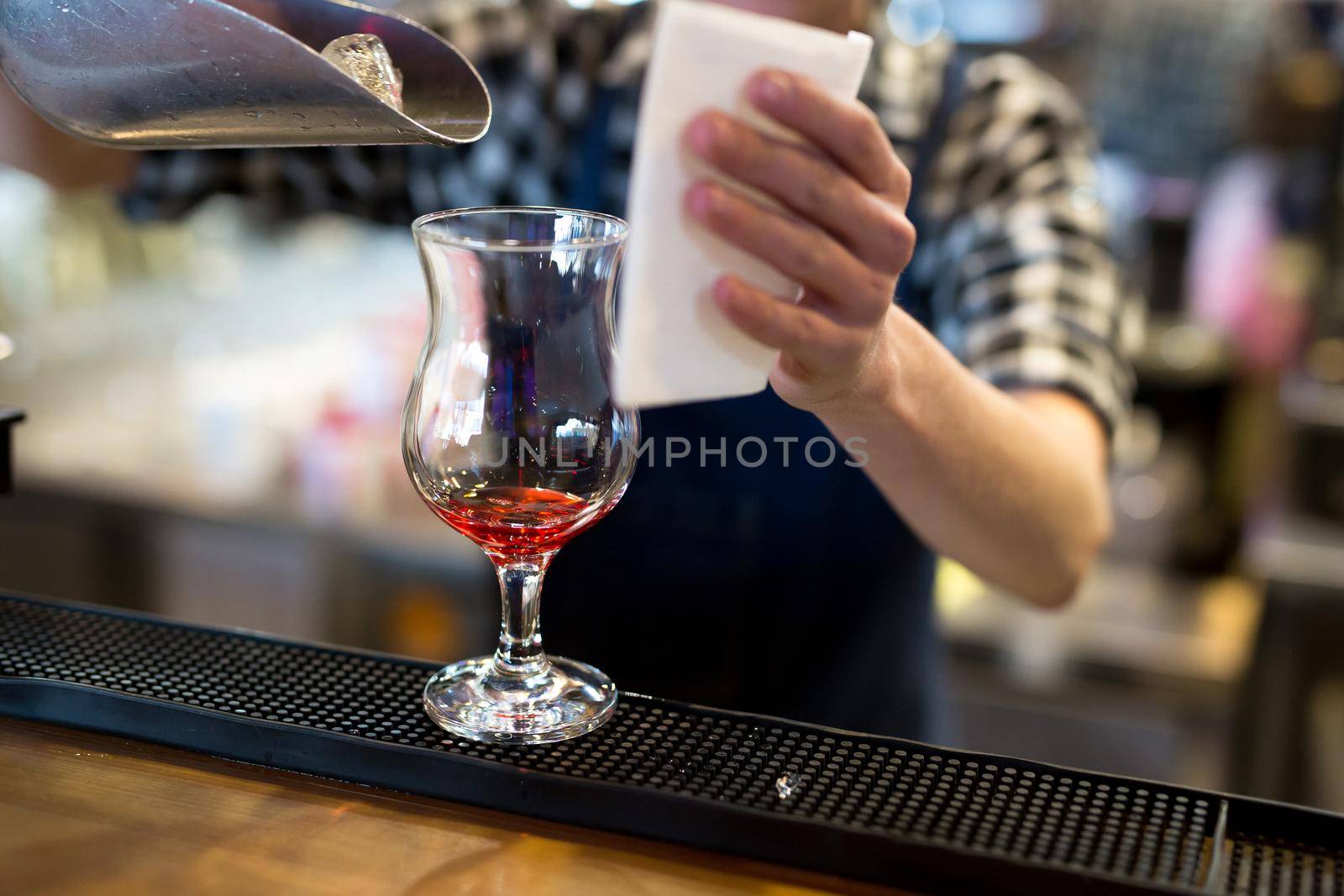 The bartender in the restaurant pours ice into a cocktail glass.