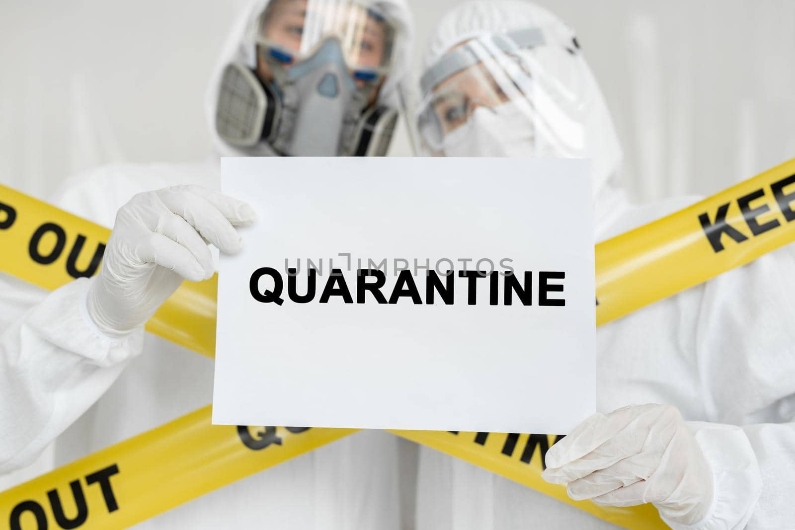 Doctors epidemiologists man and woman holding poster with sign Quarantine over white background. Yellow line Keep Out Quarantine by StudioPeace
