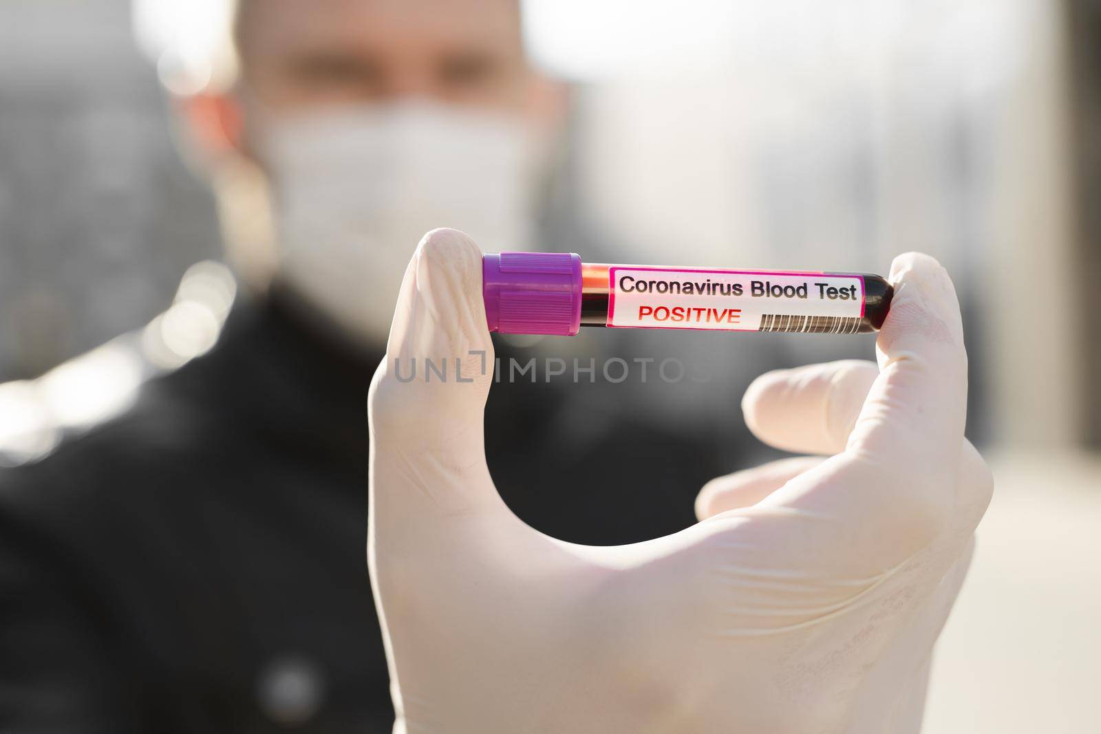 Man's hands holding a test tube with a blood sample for research new rapidly spreading Coronavirus Covid-19.