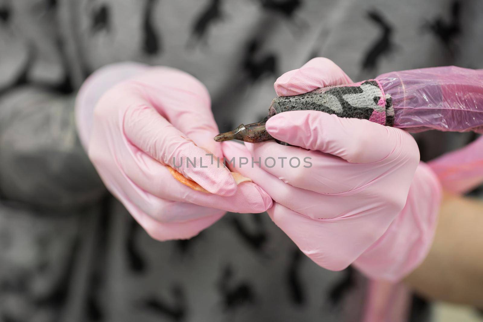 Close-up of the face of a tattooist girl with light hair, who is holding a tattoo machine in her hand. Portrait of a tattoo artist while working in a tattoo parlor.