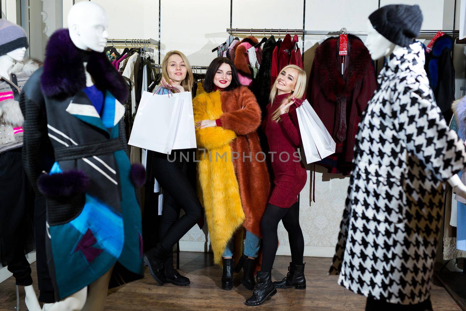 Three women trying on a fur coat in the store. by StudioPeace