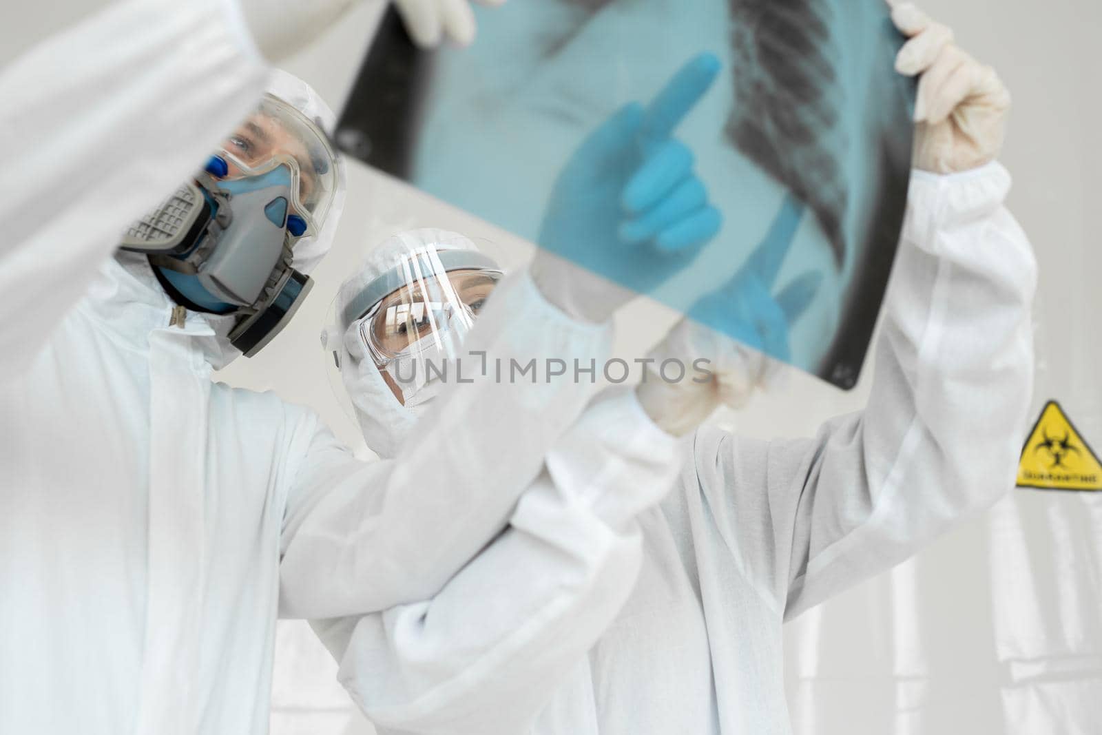 Doctors Epidemiologists examine x-ray for pneumonia of a Covid-19 patient. Coronavirus concept. by StudioPeace