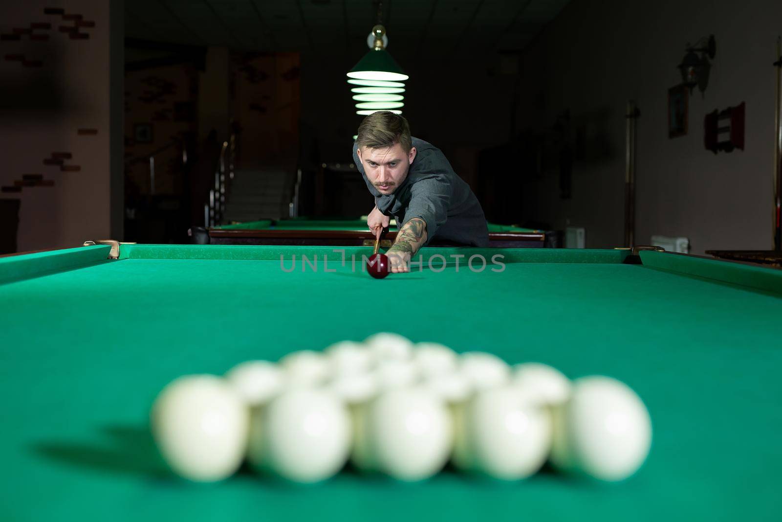 Man trying to hit the ball in billiard. Billiard room on the background.