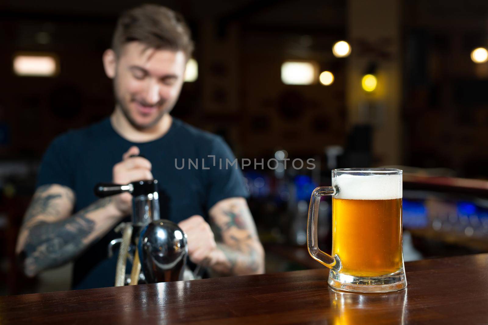 Bartender pouring from tap fresh beer into the glass in pub. by StudioPeace