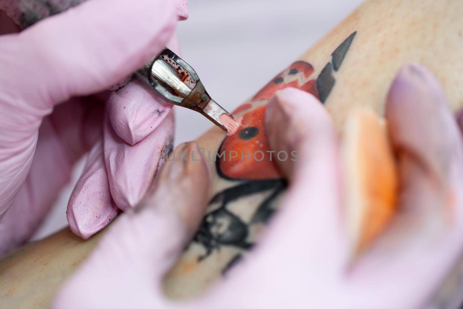 Needle tattoo machines inject a red ink into the skin of a girl. Close-up of the process of applying the tattoo on the skin. by StudioPeace