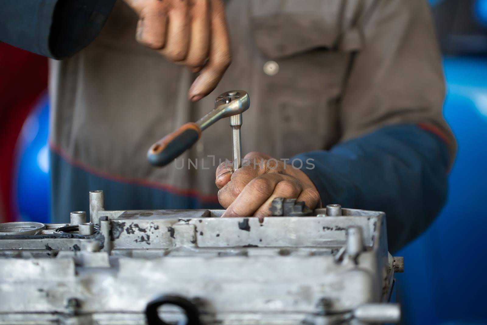 An auto mechanic repairs an internal combustion engine.