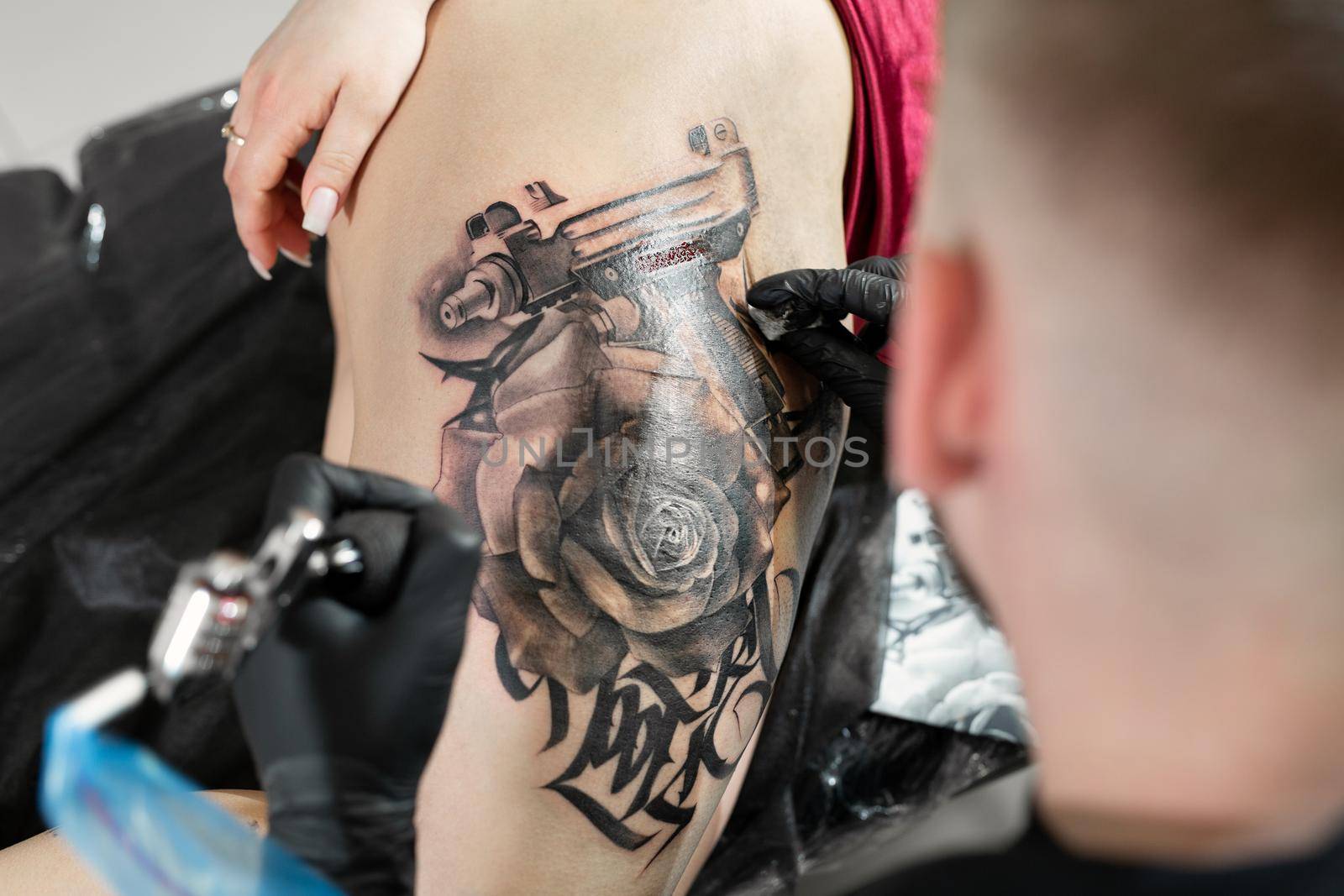Close up image of the bearded tattoo male artist makes a tattoo on a female leg. by StudioPeace