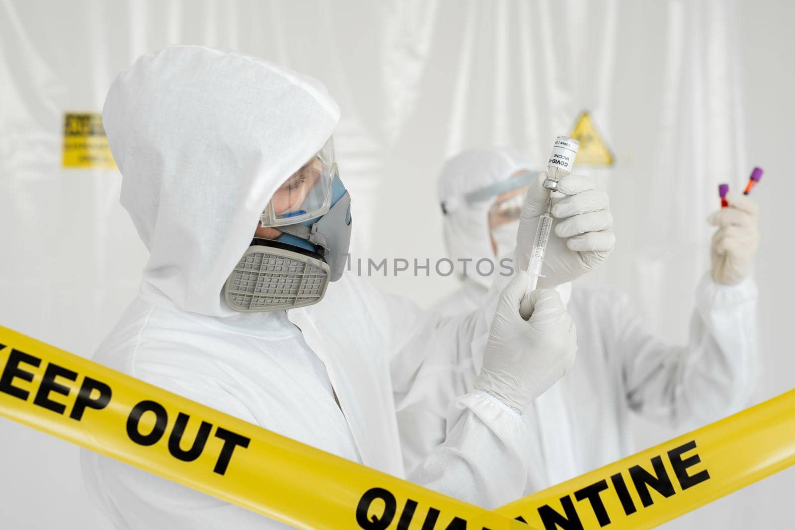 Doctor in a protective suit and mask holds an injection syringe and vaccine COVID-19. Laboratory Scientists in a Coverall Conducting a Research Vaccine by StudioPeace
