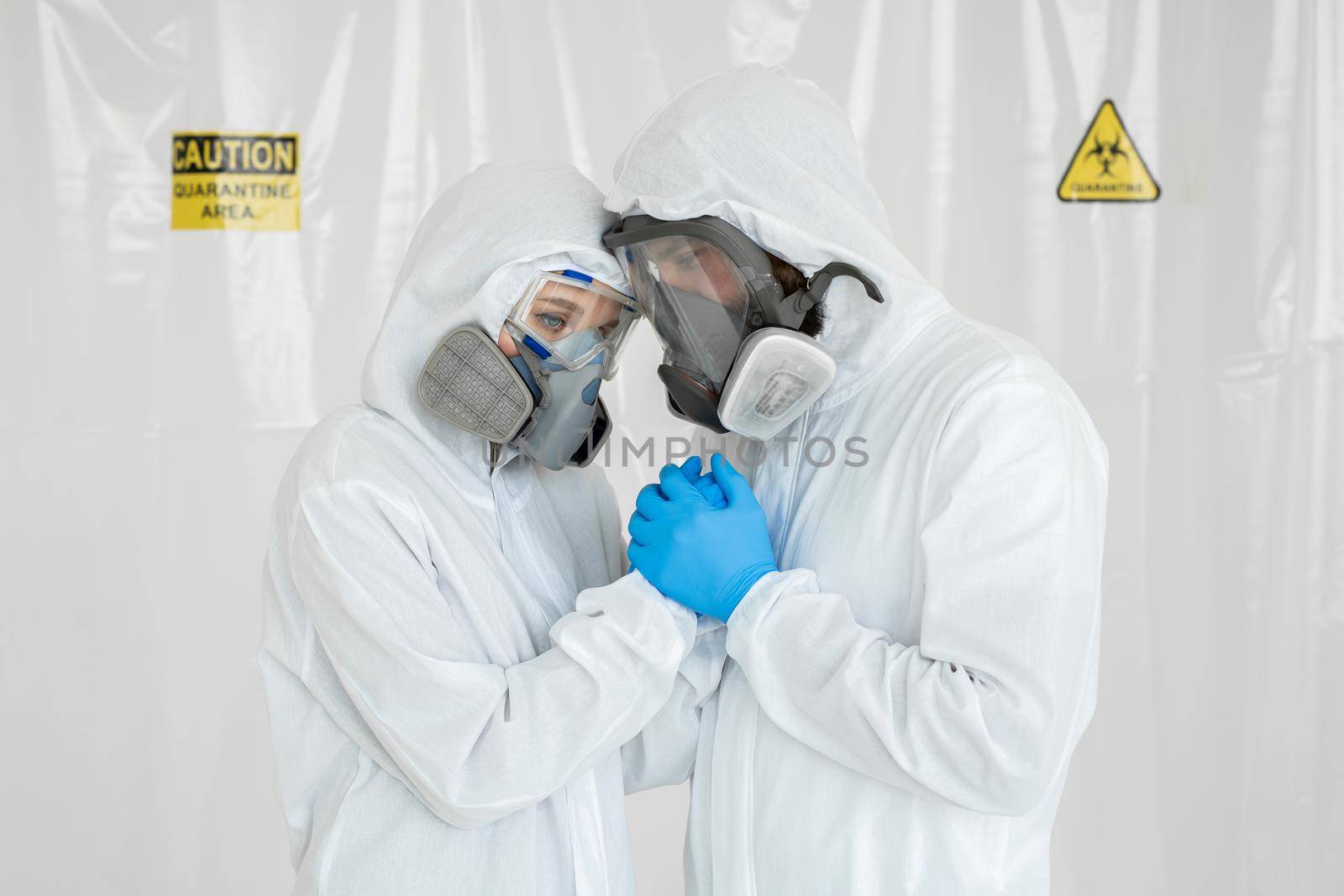 Portraits of the doctor: a man and a woman in protective suits and respirators holding hands during quarantine. Covid-19 by StudioPeace