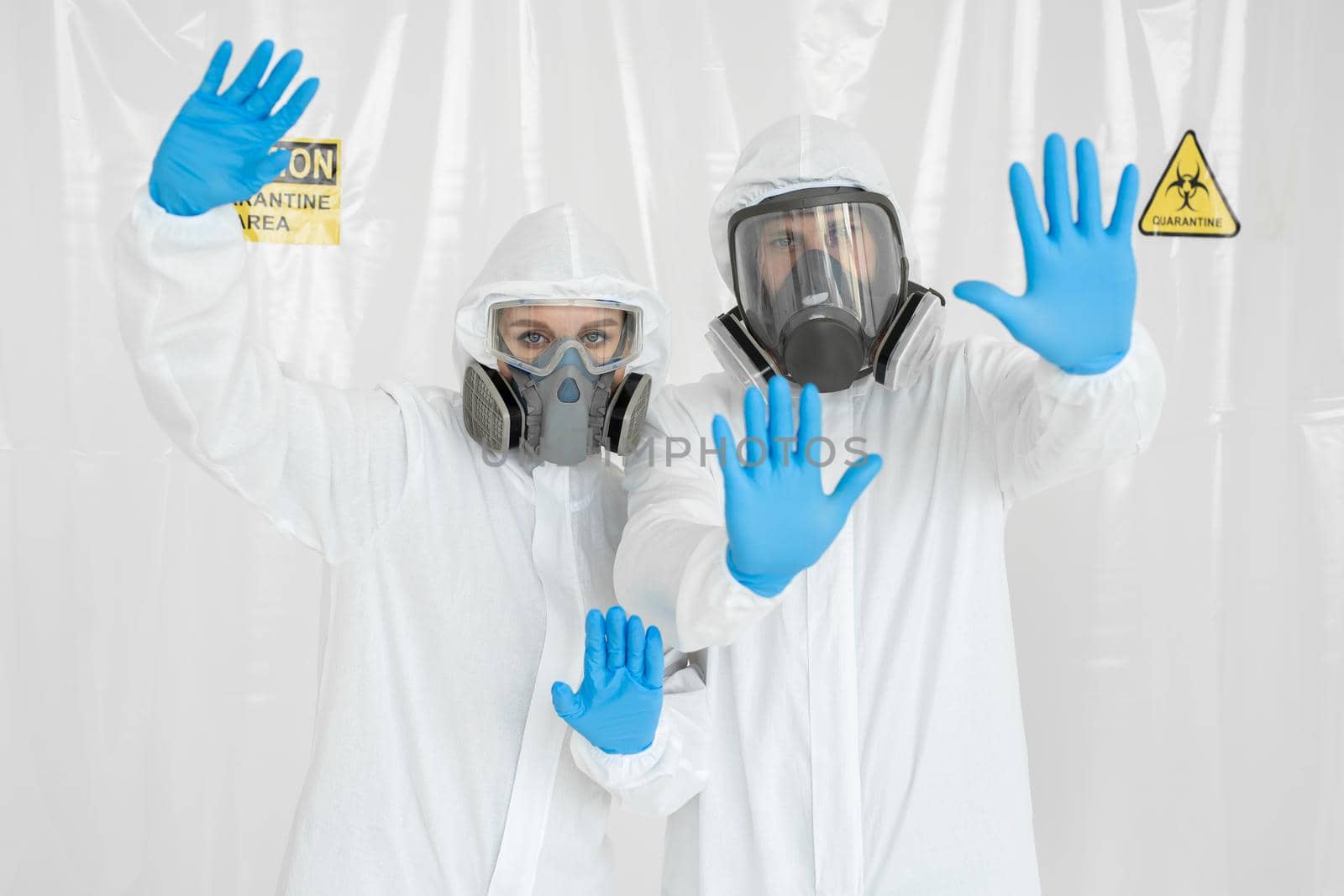 Portrait of two doctors a man and a woman in medical uniform with a protective face mask and a gloved hand showing a stop sign. Stop COVID-19 concept. The epidemic of coronavirus.