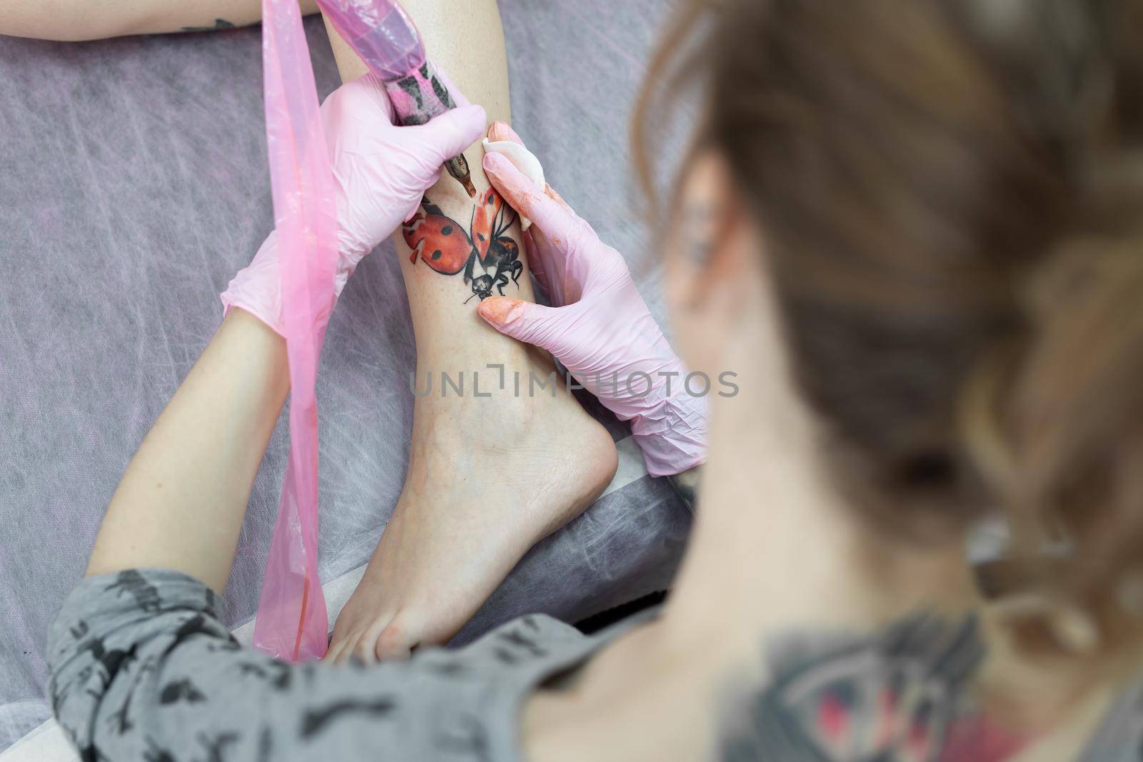 Needle tattoo machines inject a red ink into the skin of a girl. Close-up of the process of applying the tattoo on the skin. by StudioPeace