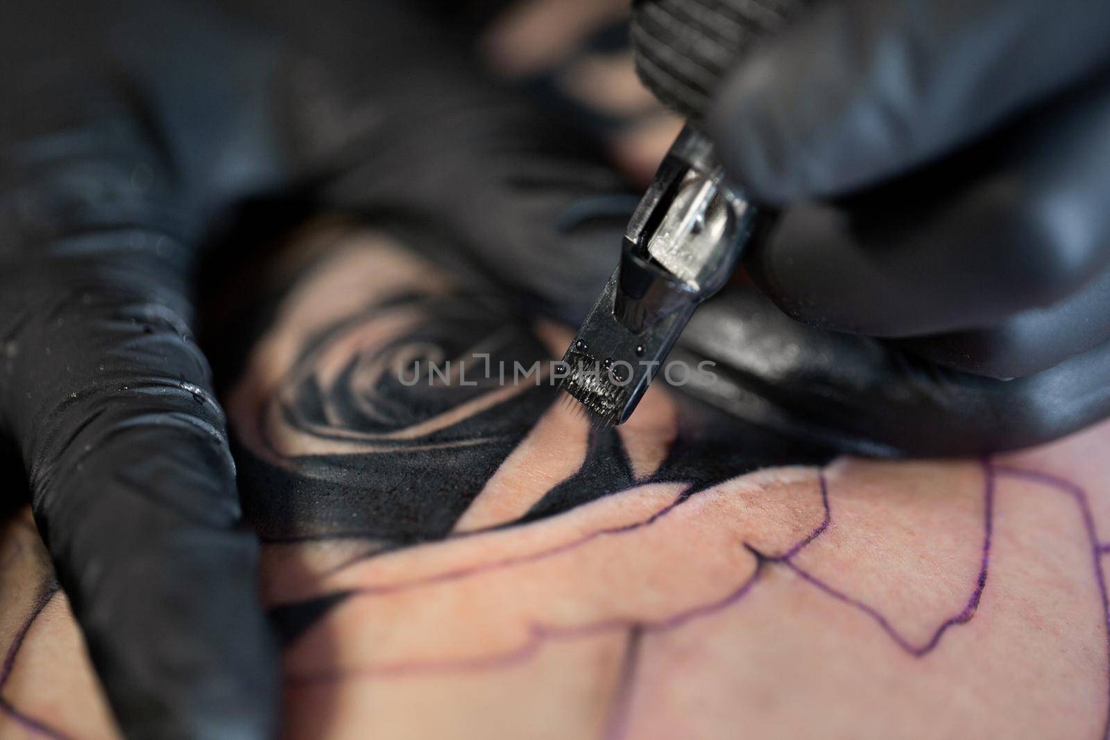 Close up image of the bearded tattoo male artist makes a tattoo on a female leg. by StudioPeace