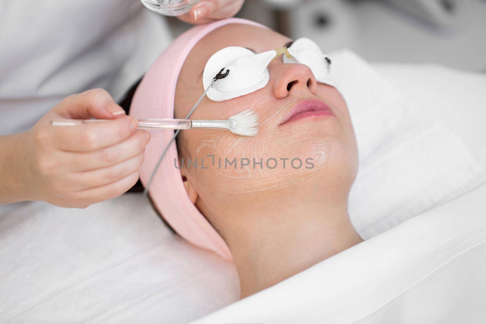 Close-up cosmetologist applies a brush moisturizing gel on the face of a young girl. Rejuvenating treatments at the Spa. by StudioPeace