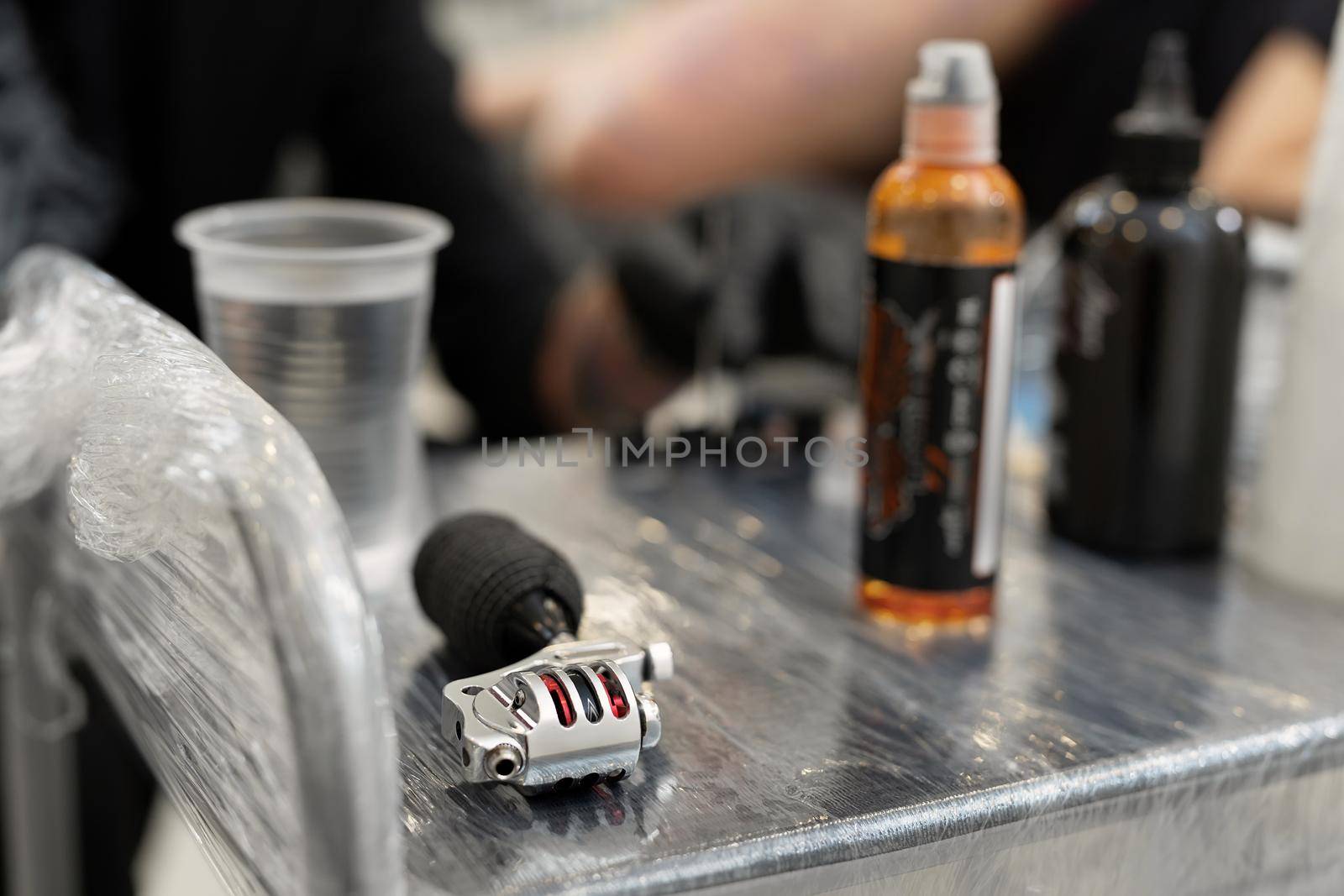 Tattoo machine and black paint are on the table in the tattoo salon