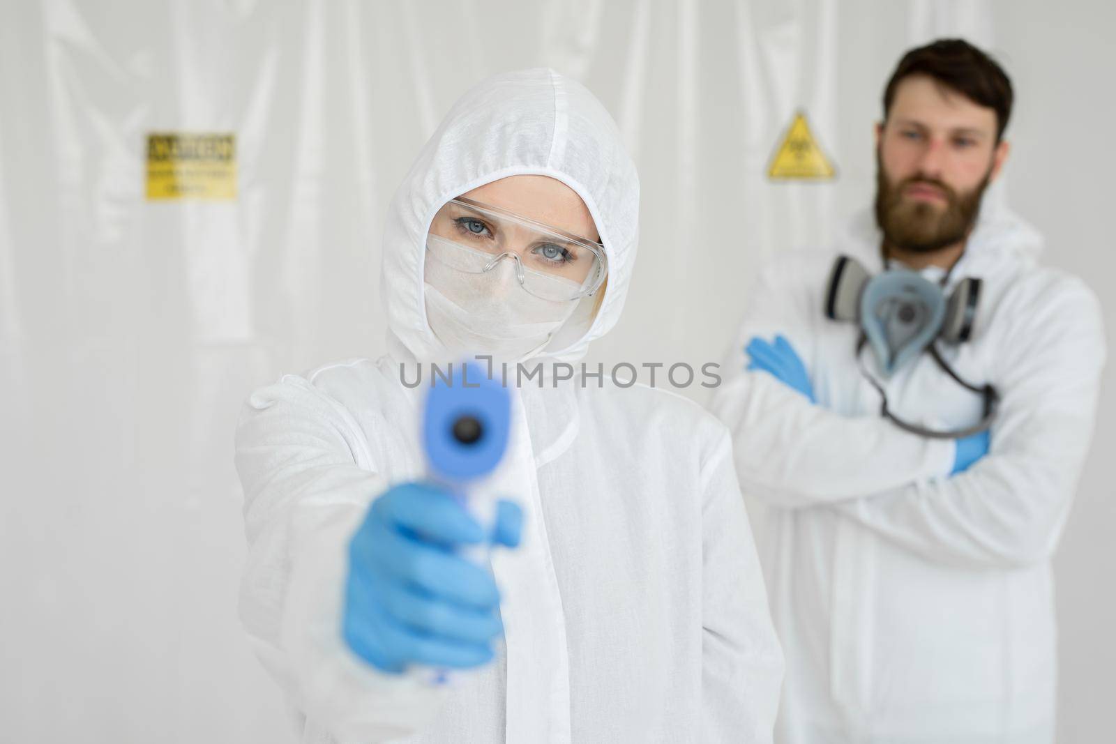 Medical professionals in protective clothing measuring contactless fever at Covid-19 test center during coronavirus epidemic by StudioPeace