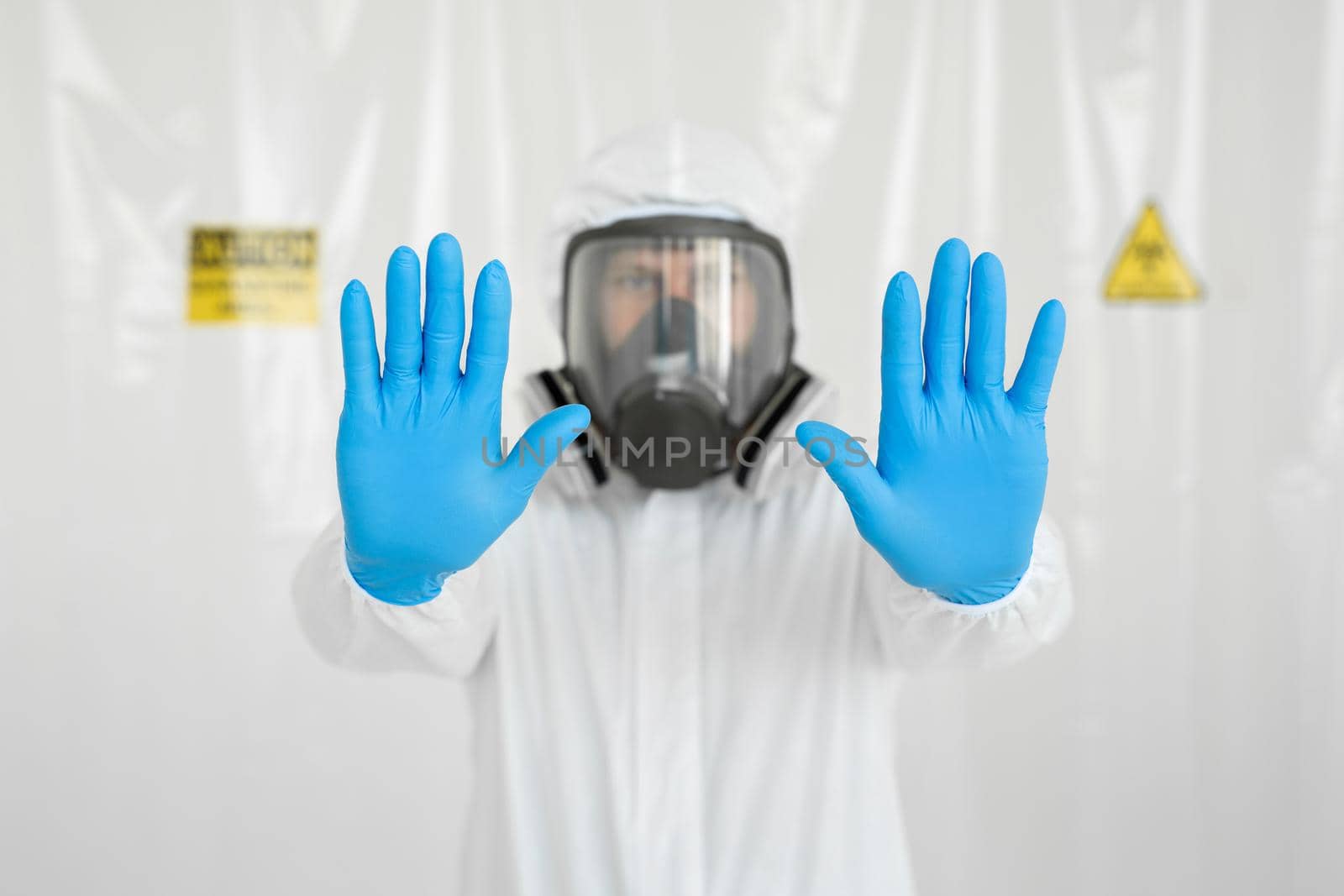 Portrait of doctor in medical uniform with a protective face mask and a gloved hand showing a stop sign. Stop COVID-19 concept. The epidemic of coronavirus.