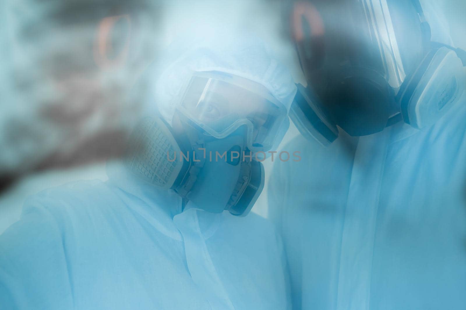 Epidemiologists in respirators examine the patient's pneumonia on a radiograph Covid-19. Concept of coronavirus by StudioPeace