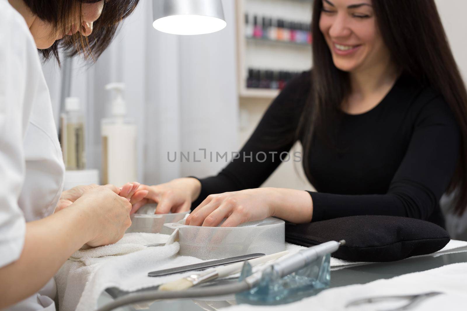 Nail Salon. Closeup Of Female Hand With Healthy Natural Nails Getting Nail Care Procedure. Hands Removing Cuticles With Professional Nail Tool, Metal Clippers. Beauty Manicure. by StudioPeace