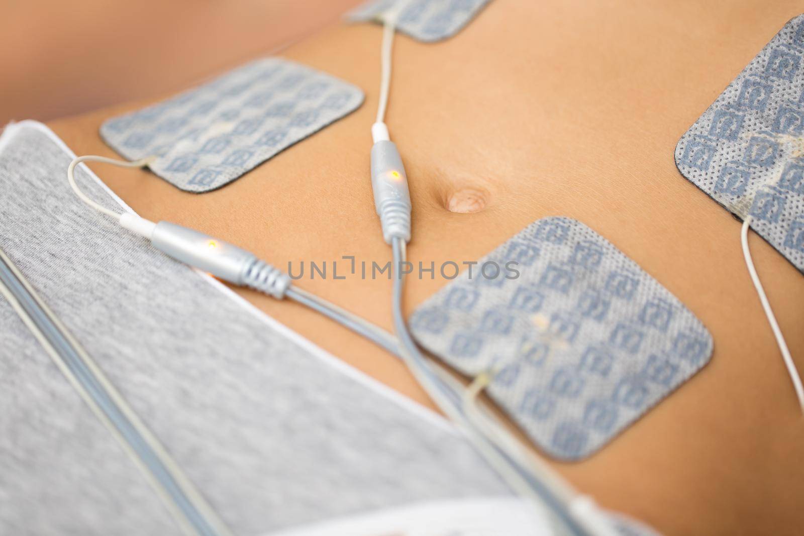Therapist applying lipomassage on girls body in spa. Close-up of biostimulating apparatus for anti-cellulite lipomassage. Hardware cosmetology
