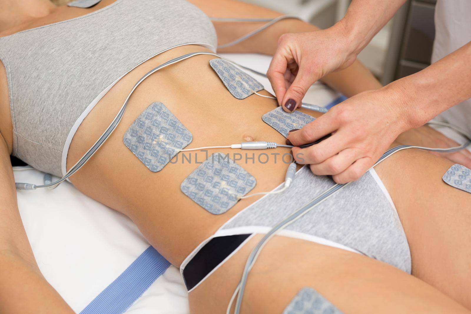 Therapist applying lipomassage on girls body in spa. Close-up of biostimulating apparatus for anti-cellulite lipomassage. Hardware cosmetology. Body care. by StudioPeace