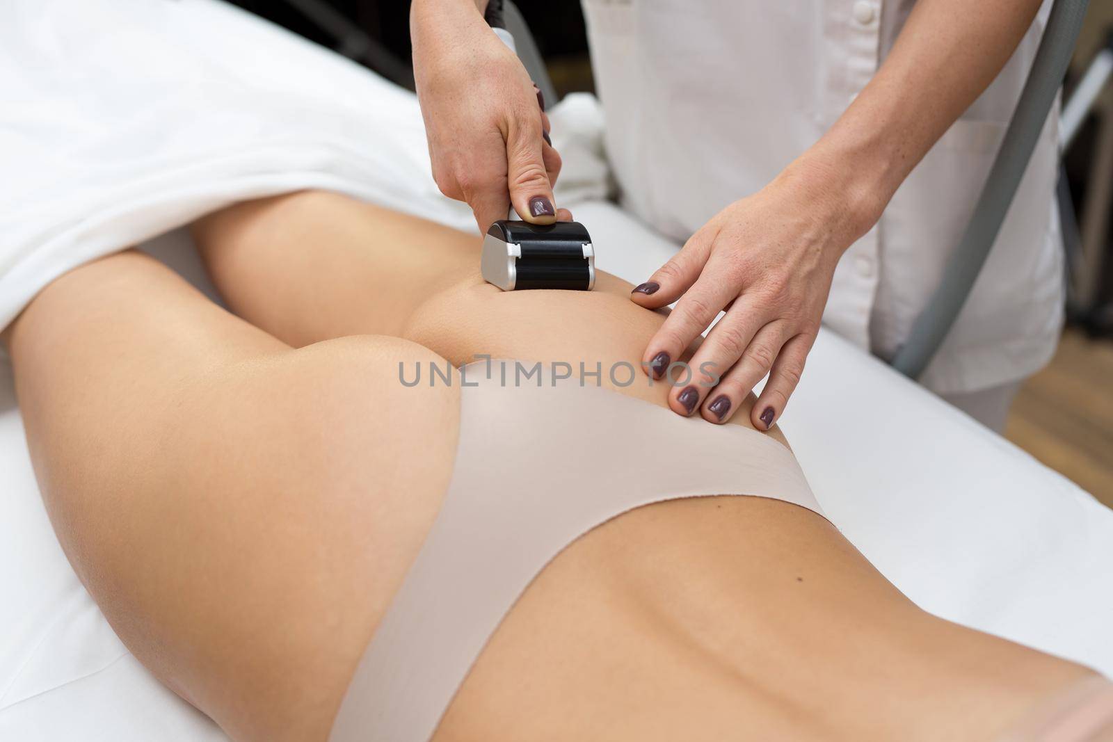 Sexy young girl is lying on the couch in a cosmetology clinic and she is given a vacuum massage with a special medical device. Hardware cosmetology. Body care. by StudioPeace