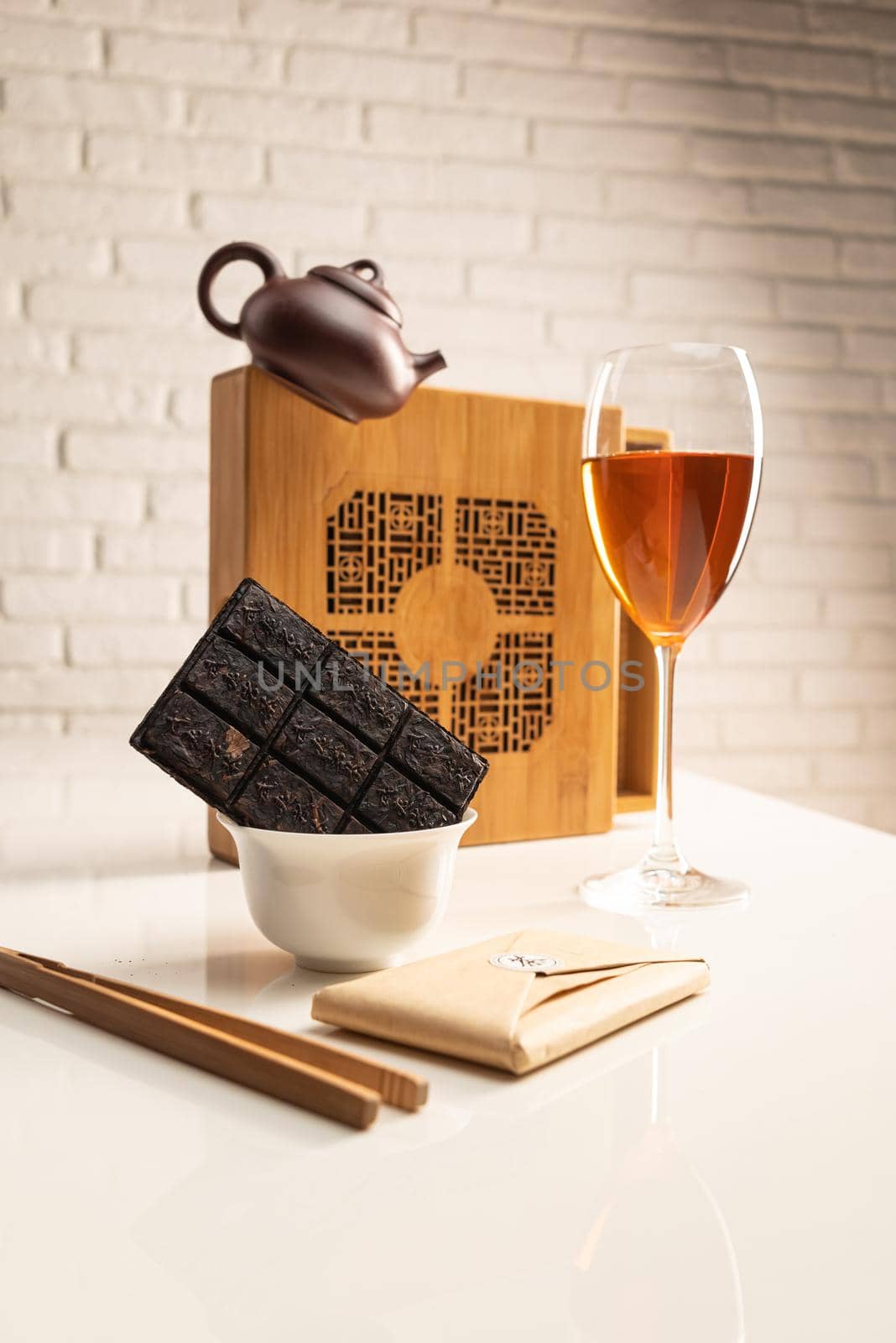 a tea table with tea and a wine glass in which Sheng Pu'er tea is poured to demonstrate the color by Rotozey