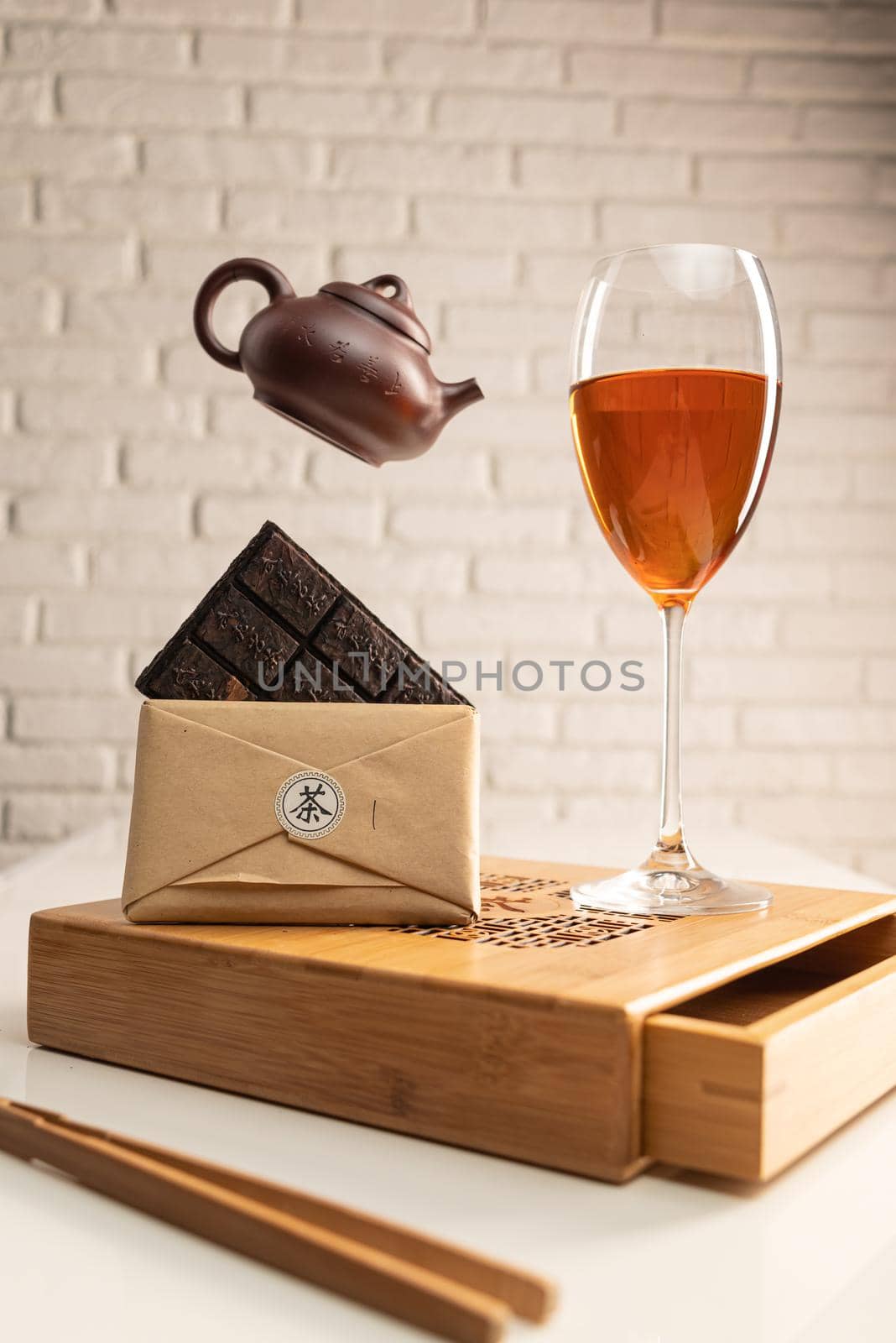 a tea table with tea and a wine glass in which Sheng Pu'er tea is poured to demonstrate the color by Rotozey
