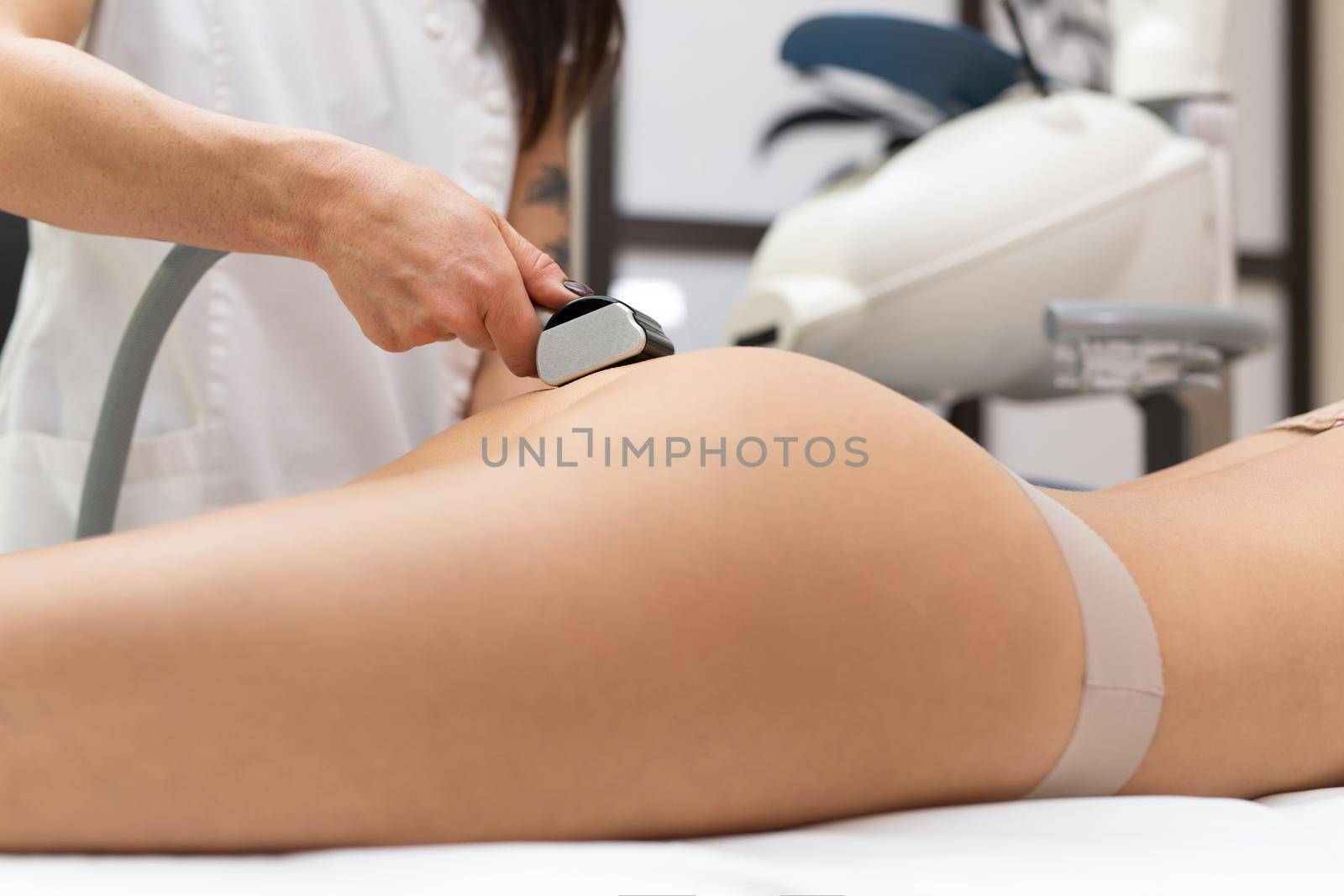Close-up of a woman masseur doing a vacuum massage of the buttocks for a young woman. Cosmetology, body and skin care. Vacuum roller massage with the possibility of ultrasonic action.
